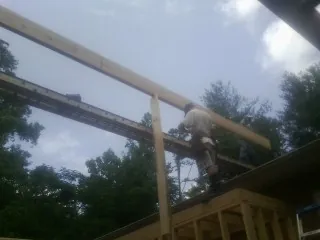 Carpenter setting a ridge beam over a new addition frame — Ice Dam Removal by Roofing Brothers in Sanger