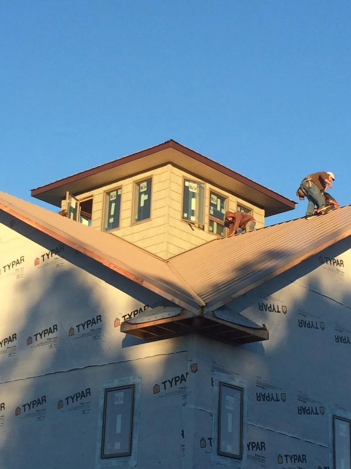 Roofers working around a rooftop cupola on a new metal roof at sunset — Roof Waterproofing in Sanger by Roofing Brothers